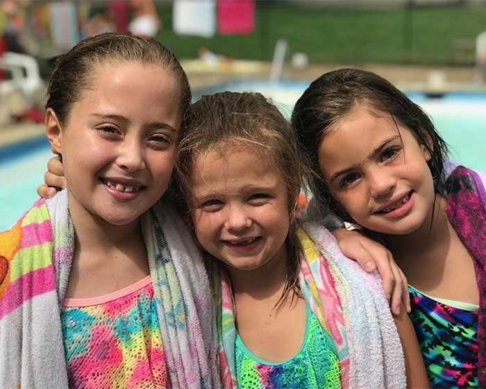 Three girls smiling at the pool